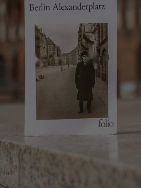 Berlin Alexanderplatz d’Alfred Döblin, posé sur une marche en pierre devant une façade de brique